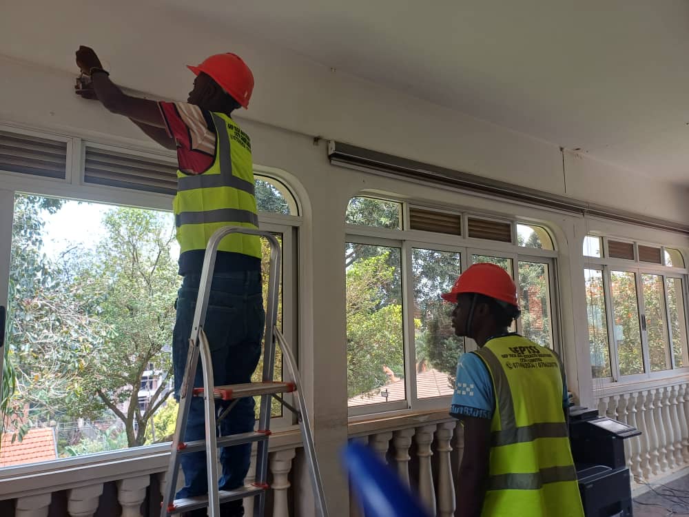 Two GEP TSS engineers installing CCTV cameras on a building verandah